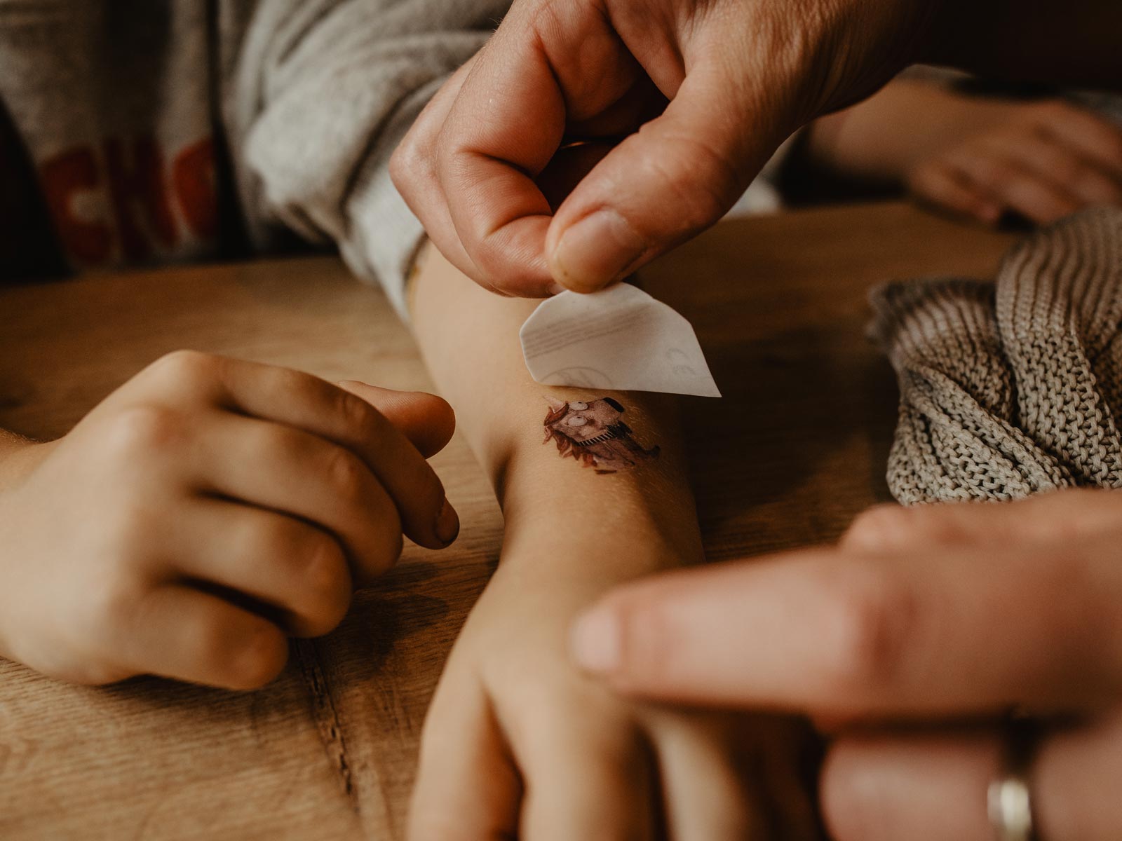 Kind beklebt Kinderarm mit Tattoos von Halfbird