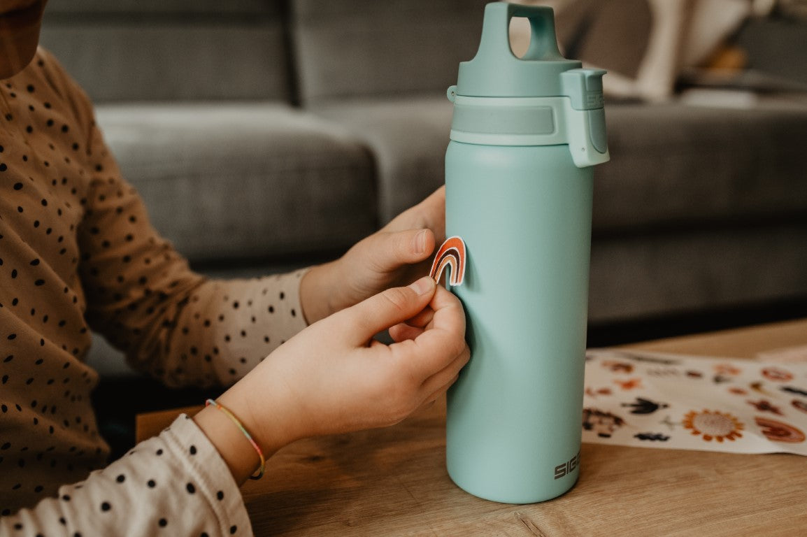 kind klebt auf seine siggi trinkflasche in mint einen spülmaschinenfesten Regenbogen Sticker von halfbird