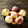 Snowbrite White yellow red peaches in wooden bowl on wood table