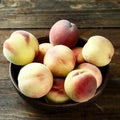 Tropic Snow yellow red peaches in wooden bowl on wood table