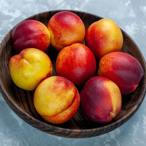 Sunracer Necatarines red and yellow fruit in wooden bowl on counter