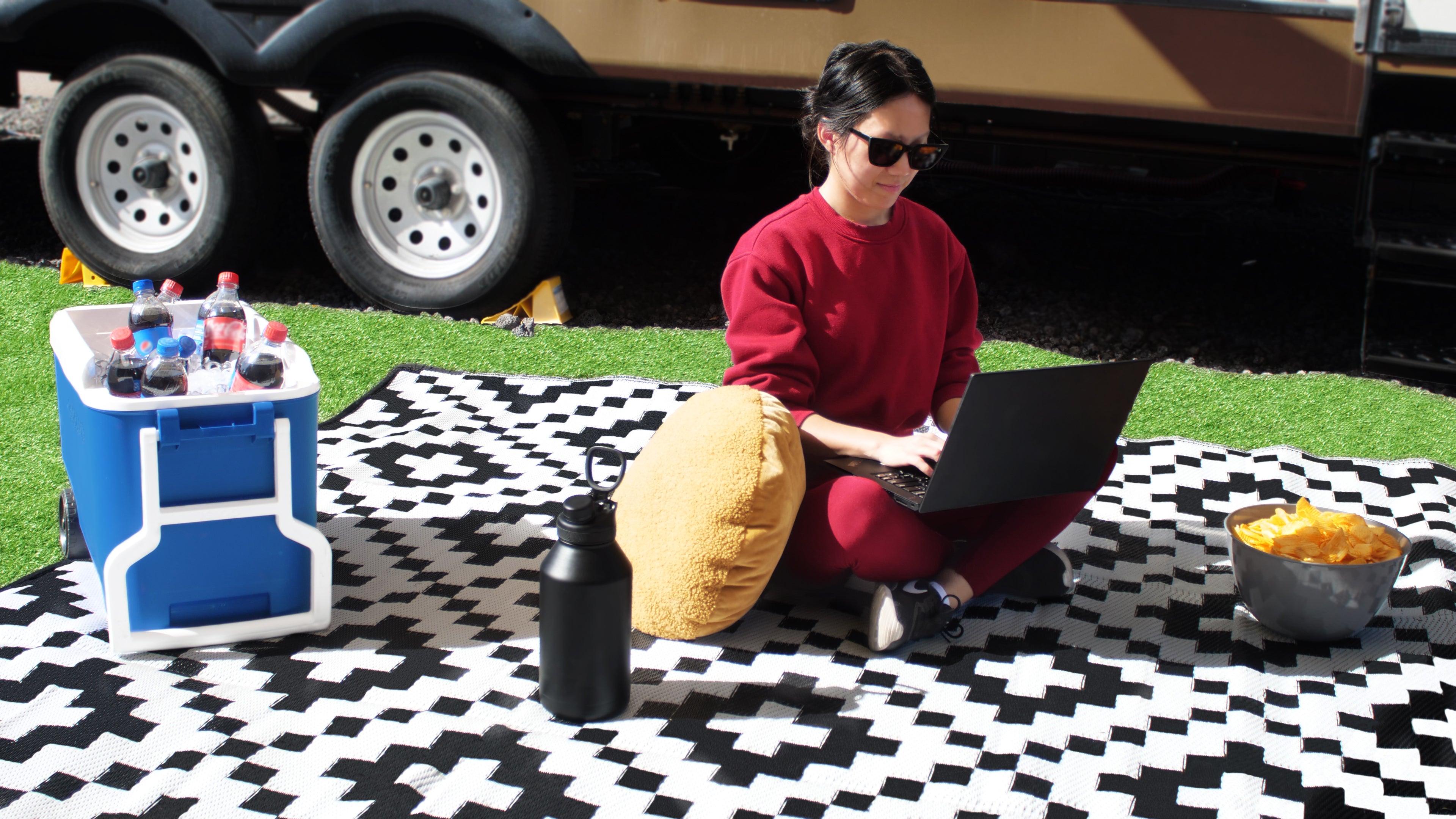 person sitting on reversible mat outside in front of rv
