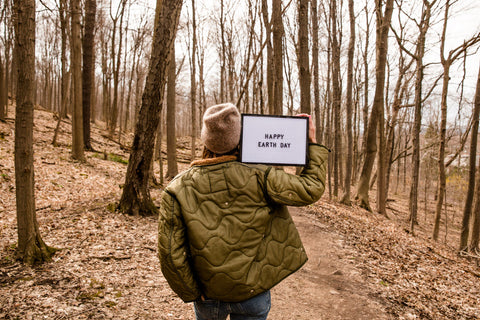 Woman Holding "Happy Earth Day" sign in forest