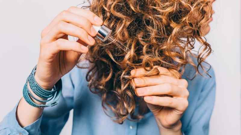 haarserum-anwendung-haaressenz-haarwachstum-gegen-haarausfall-trockene-haare-serum-treatment-frau-mit-langem-haar-locken-braun