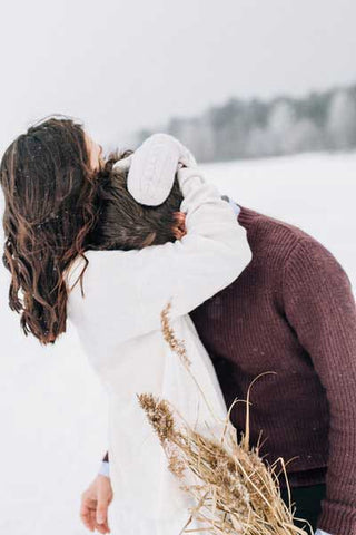 woman-hugging-man-in-sweatshirt-snow-fun-love-happiness-couple-hair-sunlight-sport