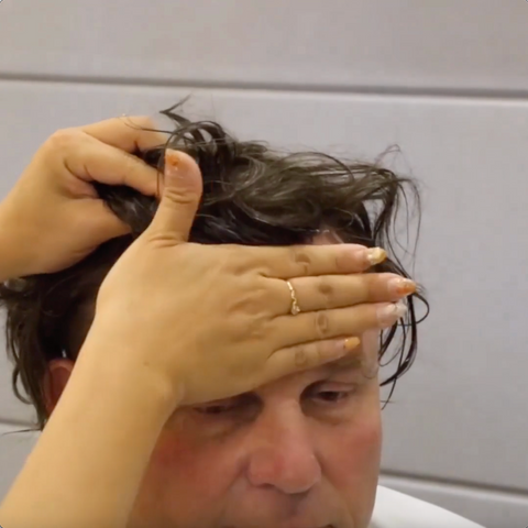 Measuring placement of hairpiece on head using hands on forehead