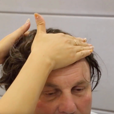 Hands pressing hairpiece firmly on to man's head