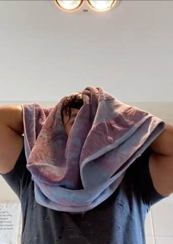 man pat drying his hair with a towel