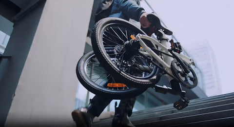 Vélo Electrique Pliant Triomphe porté dans les escaliers