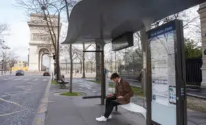 Person sitting at a bus stop near the Arc de Triomphe in Paris.