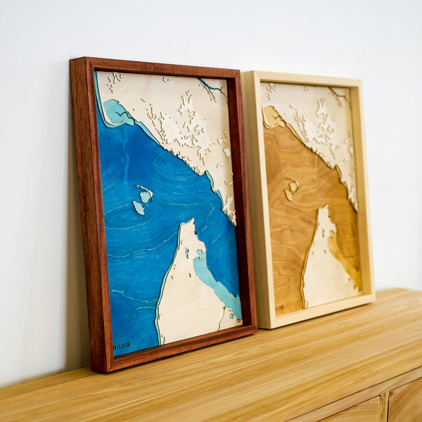 Two maps of the Gironde estuary side by side on a wooden chest of drawers: the water is navy blue on the first and brown on the second