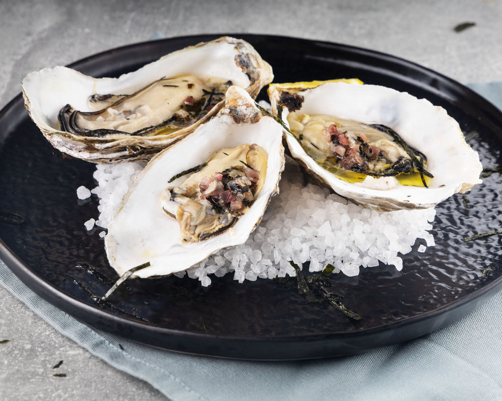 Three oysters on a bed of salt on a plate
