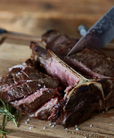 Cutting grilled and salted Porterhouse Steak