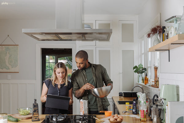 Young European female and young black male make food in their home kitchen together. 