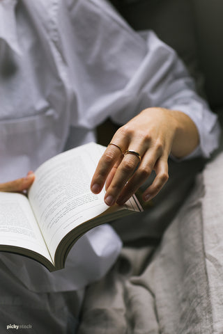 Close up of lady delicately turning the pages of a paperback book.