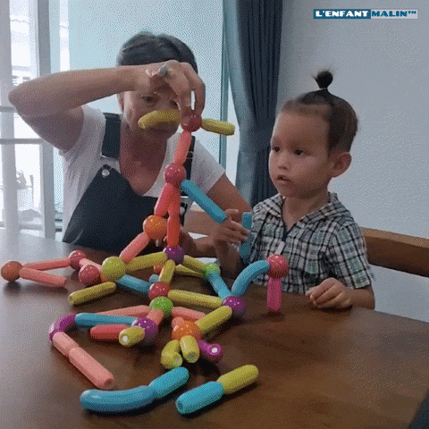 grand-mère partage un moment avec son petit-fils de 3 ans, ils jouent au jeu de construction magnétique, jeu aimanté