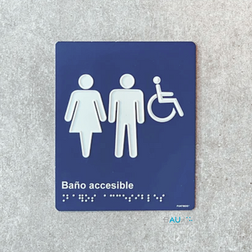 Señalética Baño Accesible con íconos de mujer, hombre e ícono de silla de ruedas, sobre fondo azul y braille en blanco. 