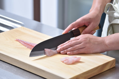 Slicing raw fish on a wooden cutting board