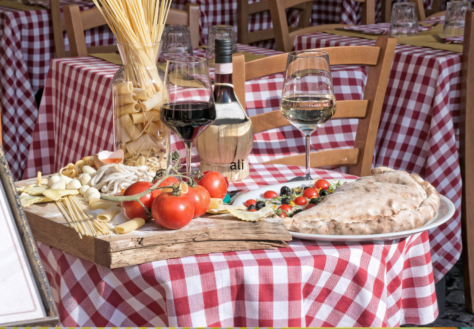 Table set with Italian wine, fresh veggies and pasta