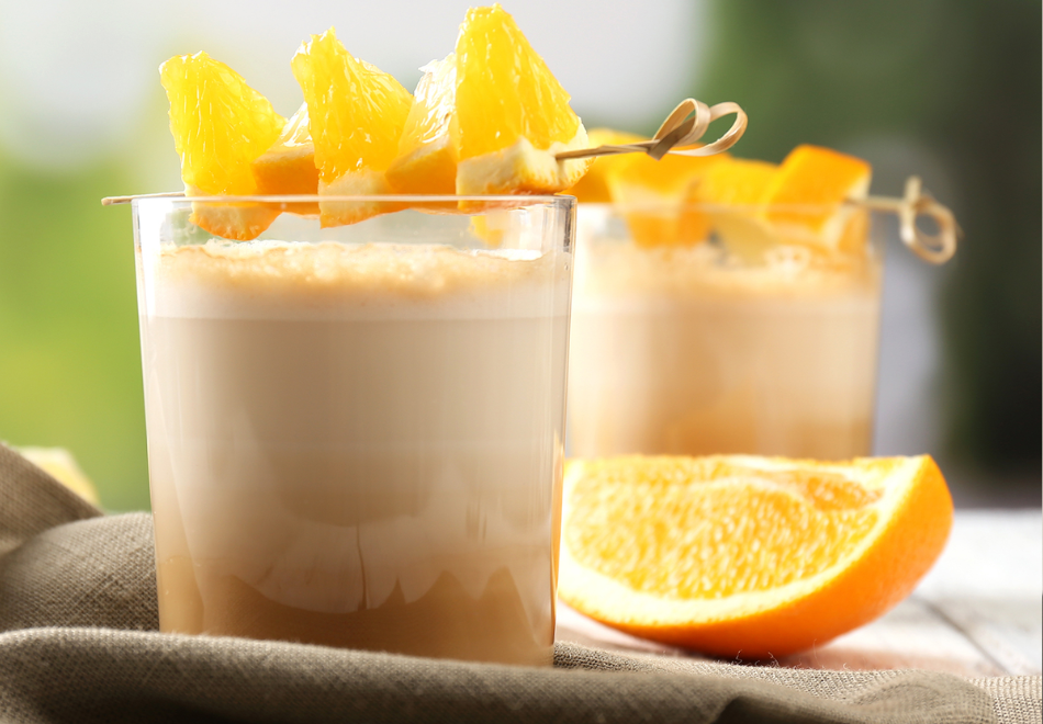 cold drink with an orange garnish on a bamboo knot pick