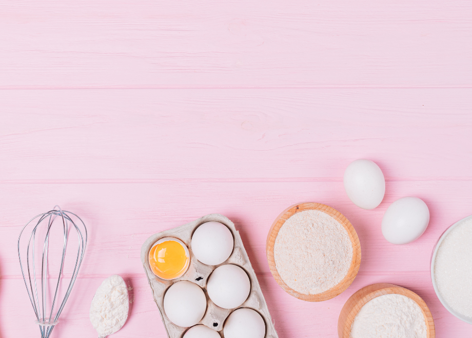 baking utensils and eggs against a light pink background