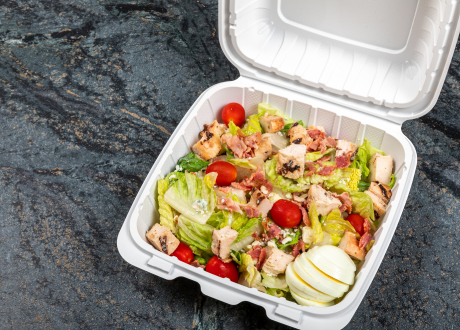 mineral filled plastic large takeout container. there is a chef's salad inside the container