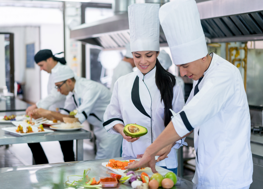 kitchen staff working and wearing various types of chef hats