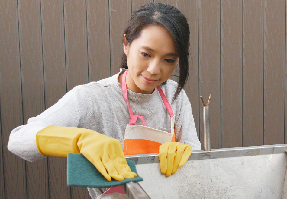Person cleaning an outdoor sink with a green scouring pad