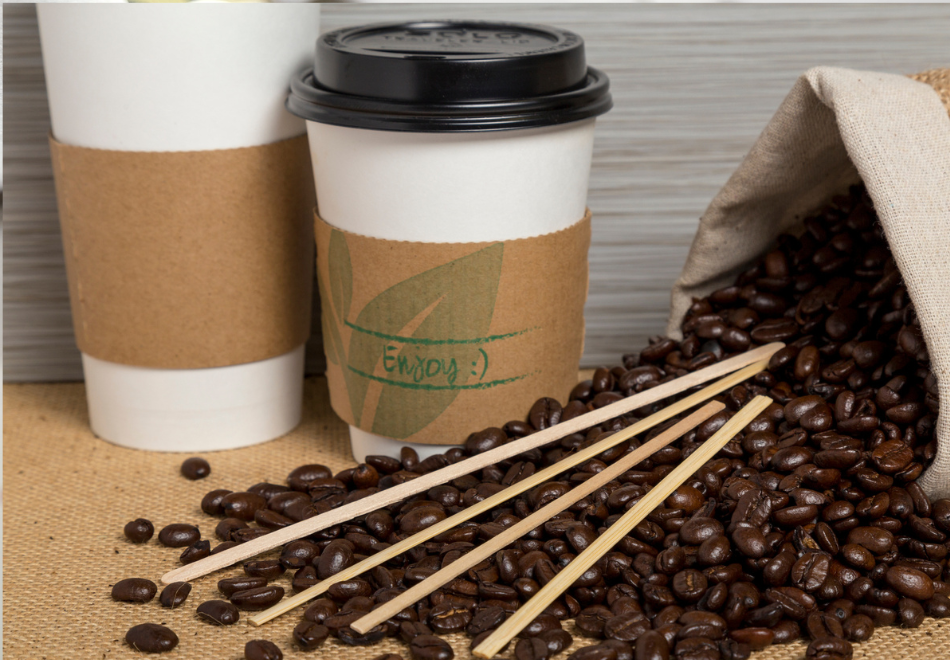 coffee beans next to takeout coffee cups with cup sleeves on them