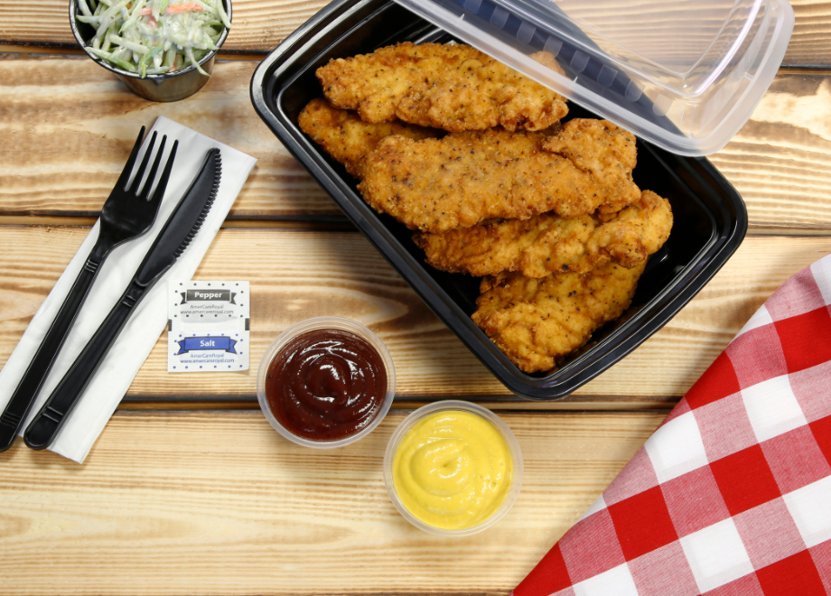 fried chicken takeout in a plastic takeout container with dip and cutlery to the side