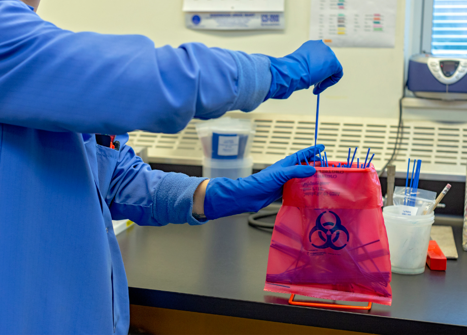 person wearing blue latex gloves and working in a lab
