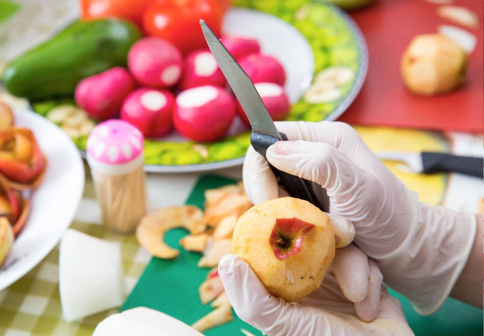 person wearing nitrile gloves and peeling an apple