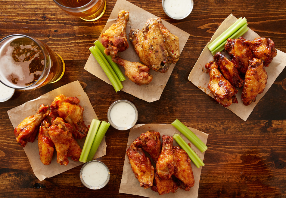 4 types of chicken wings on a table with ranch dipping sauce