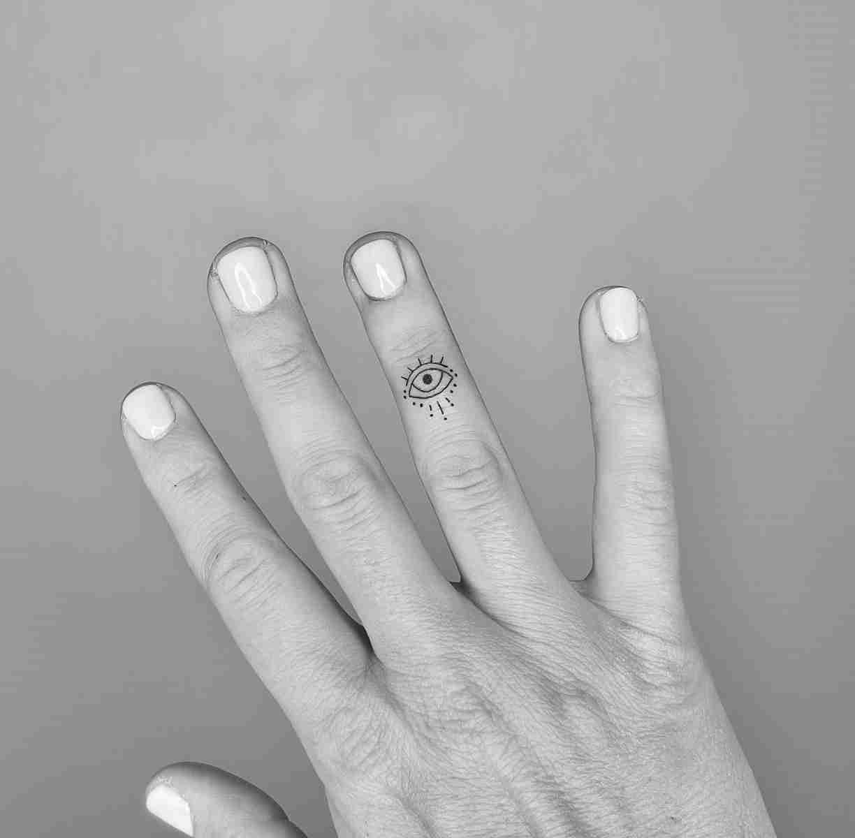 Minimalist evil eye tattoo on the finger