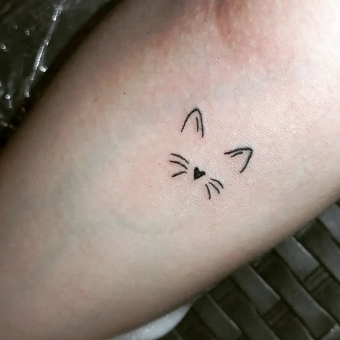 Minimalistic cats tattooed on the wrist.