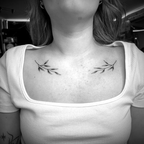 Fine line butterfly tattoo on the collarbone