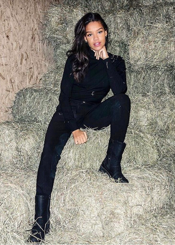 Woman dressed in black sitting on a pile of hay