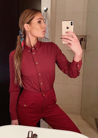 Bathroom mirror selfe of a woman dressed in red button down shirt and breeches