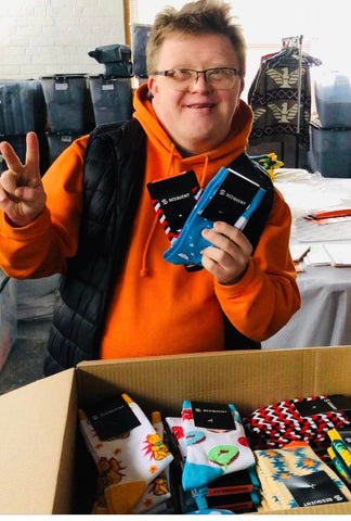 Man with Down Syndrome Holding Funky Stand Out Socks With Custom Sock Tag Header For Corporate Company