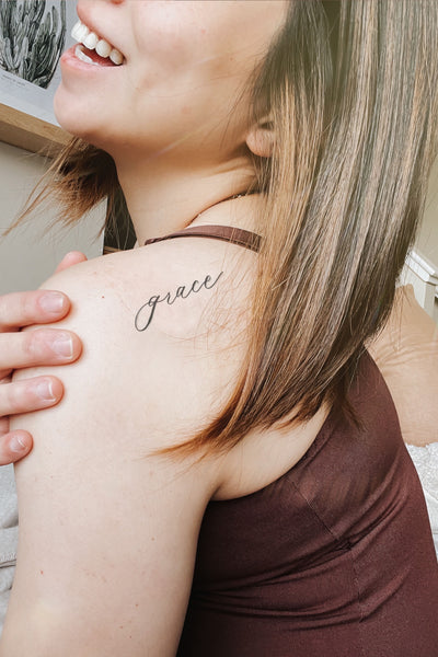 By grace lettering tattoo on the tricep