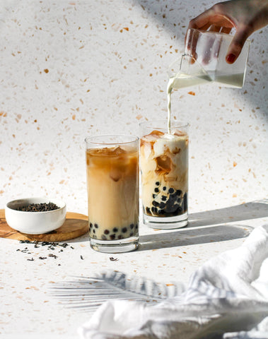 Cha Community Waco Cha boba tea drinks and loose leaf tea in a small white bowl. A shadow of a plant is toward the bottom right of the photo 