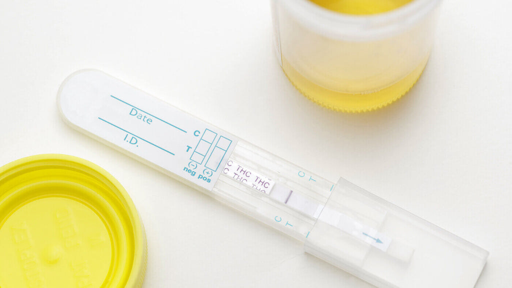 THC Drug Test for Home Use and Opened Cup for Urine Sample on White Table
