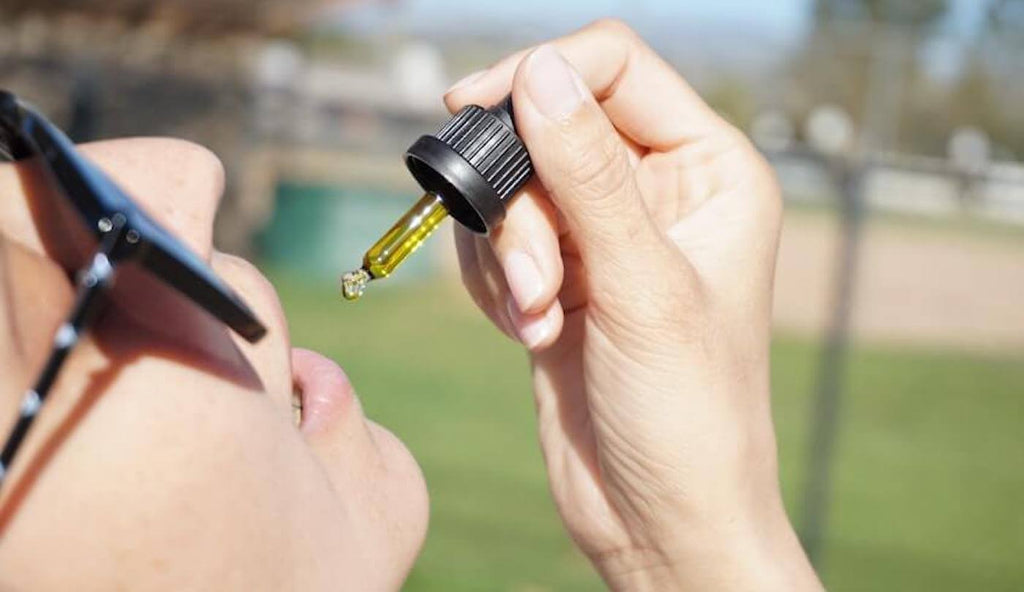 Woman Taking Drops of CBD Containing 0.3% of THC