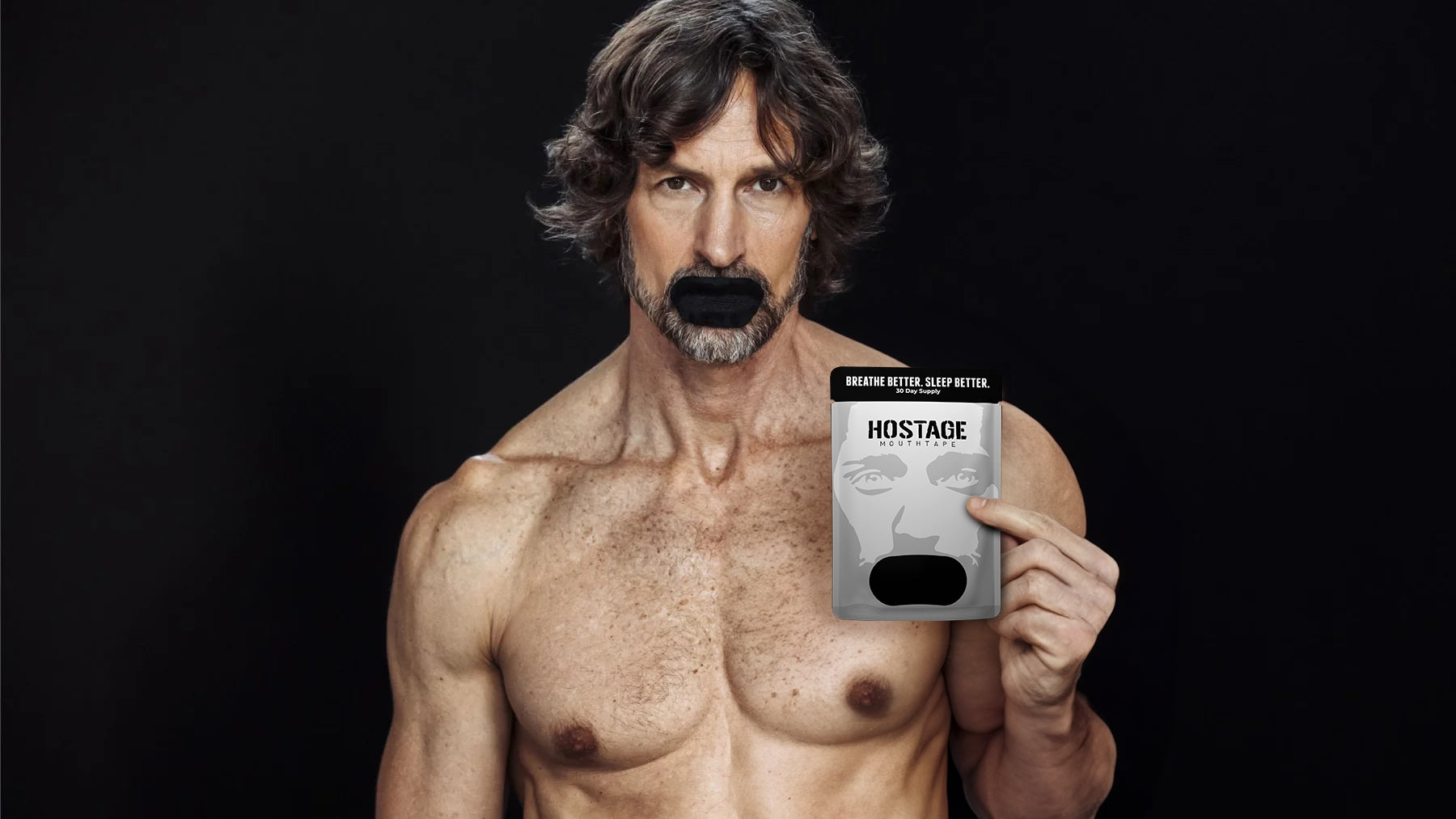 Shirtless man with taped mouth holding a product box with 'HOSTAGE MOUTHTAPE' text.