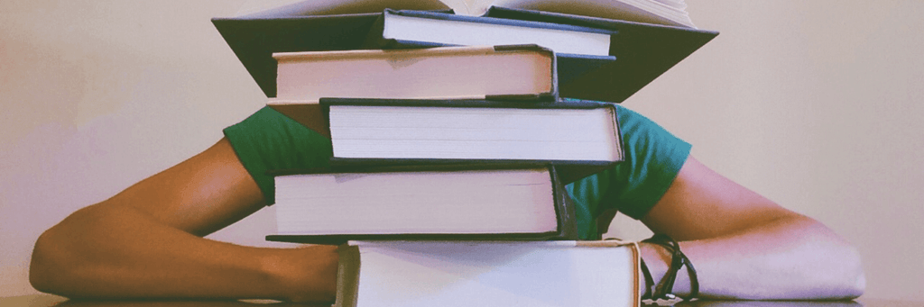 pile of books in front of a student