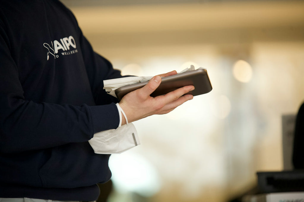 Person using disinfectant wipe to clean electronic device