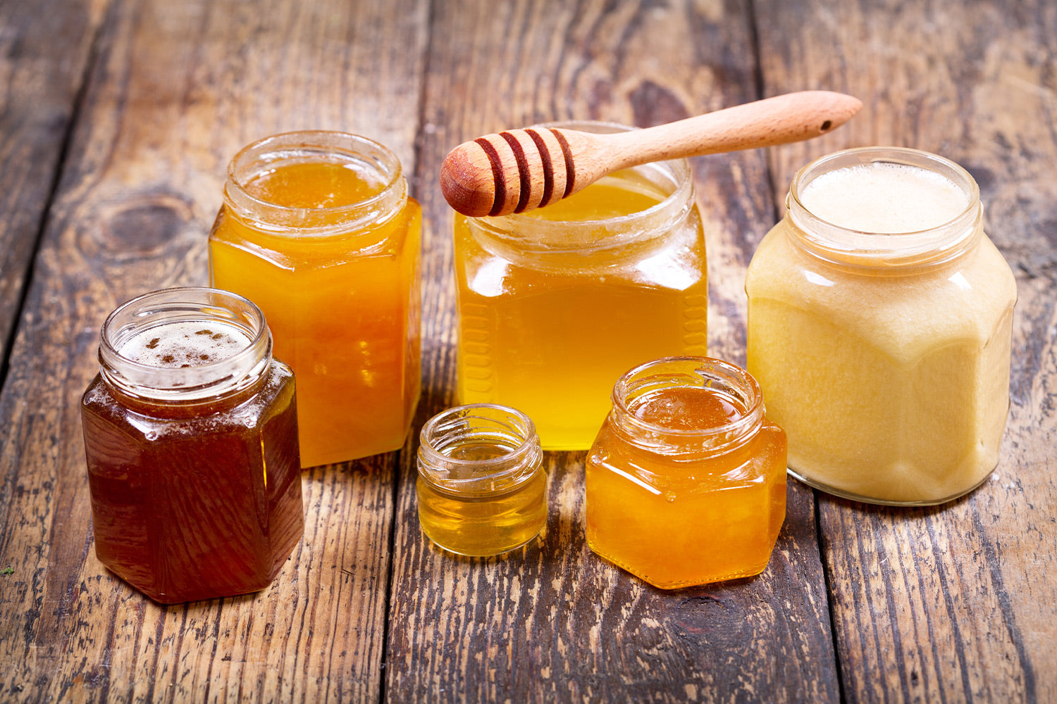 Various types of honey sitting on a wooden table