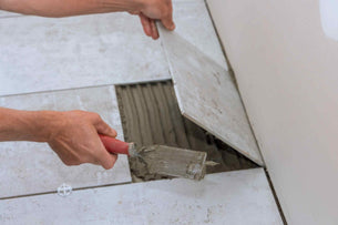 A worker cutting underneath clay tiles