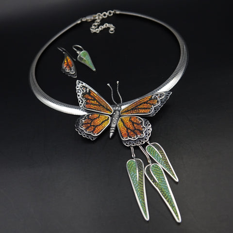 monarch butterfly necklace with mismatched earrings. One is a monarch butterfly wing and the other is a eucalyptus leaf.