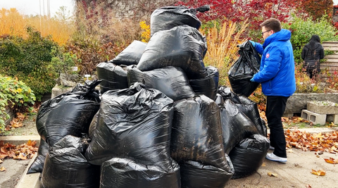 A pile of garbage bags full of coffee chaff for donation, a Zavida employee stands beside them in the photo